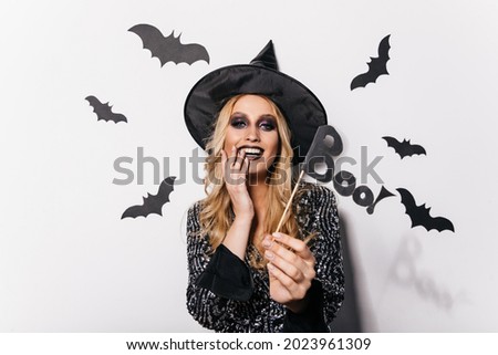 Amazing young woman posing in halloween with bats. Attractive blonde girl enjoying carnival.