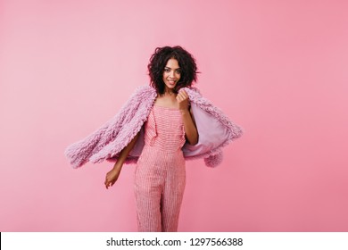 Amazingly Attractive Lady With Feline Cat's Bold Gaze Boldly Looks Into Camera. Girl Turns To Side Of Camera, Showing Off Her Lilac Coat