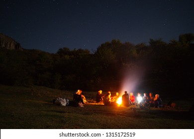 amazingly beautiful landscape with a view of the starry sky in the mountains of Crimea and a group of tourists singing songs by the fire with a guitar