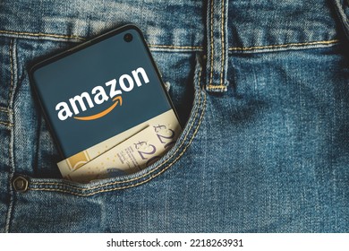 Amazon App Logo On Phone With British Pounds Cash Money In Blue Jeans Pocket. SWANSEA, UK - MARCH 28, 2021.