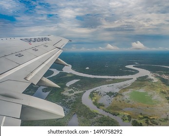 Amazonia, Brazil - November 25, 2018: From Airplane Window. Wing Of An Airplane Flying Above The Clouds Over Amazon River. Top View Of Amazon Rainforest. Peru, Brazil. Colombia.