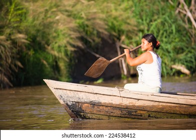 AMAZONIA, PERU - NOV 10, 2010: Unidentified Amazonian woman rows a wooden boat. Indigenous people of Amazonia are protected by COICA (Coordinator of Indigenous Organizations of the Amazon River Basin)