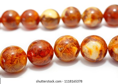 Amber. Beads made from natural yellow brown amber mineral on a white background. Fashionable jewelry amber beads from round and oblong beads. Sun stone as a jeweler raw material. Frozen Resin Fossil - Shutterstock ID 1118165378