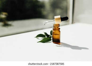 Amber bottle with serum or essential oil. Natural organic cosmetic, aromatherapy message oil. A drop of oil at the end of a pipette