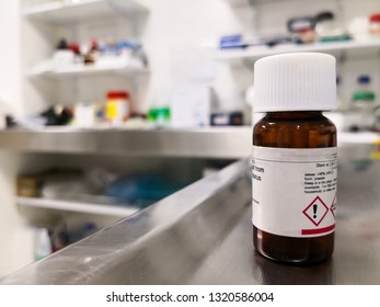 Amber Bottle For Storage Of A Chemical Substance In A Scientific Laboratory. Symbols Of Attention And Danger On The Label. Hazardous Material. Colorful Background With Science Concept. 