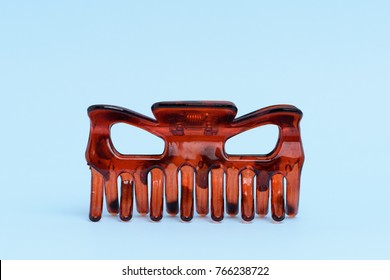 An Amber Colored Hair Claw Clip Isolated On Light Blue Background.