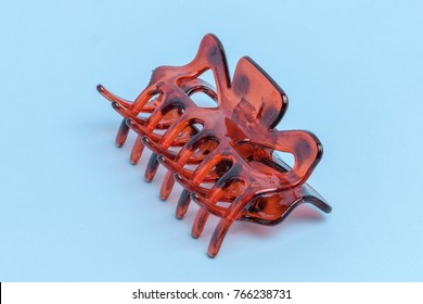 An Amber Colored Hair Claw Clip Isolated On Light Blue Background.