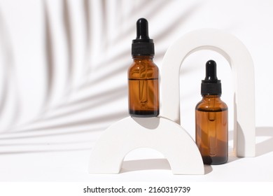 Amber glass bottle with dropper pipette with serum or essential oil in arch with palm leaf shadow. Skin care cosmetic. Beauty concept for face body care - Shutterstock ID 2160319739