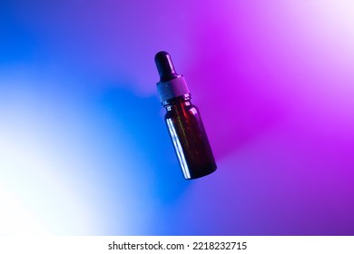 
amber glass dropper bottle with black cap in neon vibrant blue and purple lighting. Skin care products, natural cosmetics. Beauty concept for face and body care - Powered by Shutterstock