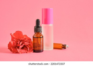 Amber Glass Dropper Bottle And Perfume Bottle And Hibiscus Flower On Pink Background Copy Space Mock Up, Serum Or Oil With Hibiscus Extract