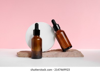 Amber glass dropper cosmetic bottle, white podium. Natural skin care SPA beauty product design. Mineral organic oil on pink background. Mock-Up. Oily pipette. Face and body treatment. Front view. - Powered by Shutterstock