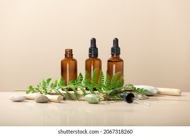 Amber glass transparent bottles on wooden podium with Jade face roller, leaves and natural stones. Natural organic cosmetic packaging, luxury beauty products for anti age face massage