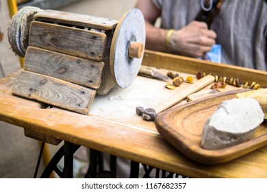 Amber Jewellery maker at work. Process of making amber beads. Shaping amber with a vintage wooden polishing tool. Traditional polishing wheels for fine grinding and detailing of a raw amber chunk. 