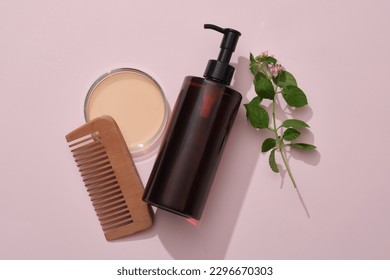 A amber pump bottle with comb, petri dish filled liquid and lantana camara on pink background. Mockup for shampoo of natural extract. Tropical herbal ingredients good for strong and smooth hair - Shutterstock ID 2296670303