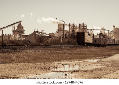 Amber Smoggy Skies , Pollution And Climate Change. Factory In Texas Producing Fossil Fuel Smoke Stack And Train Tracks Leading To Industrial Revolution Style Like