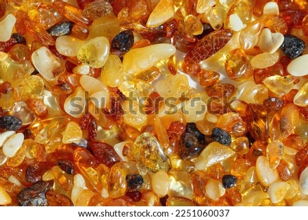Amber texture background, small stones yellow orange gradient color. Natural gemstone mineral material for jewelry. Top view Amber textured fon. Sunstones pieces ancient resin. Transparent pieces gem.