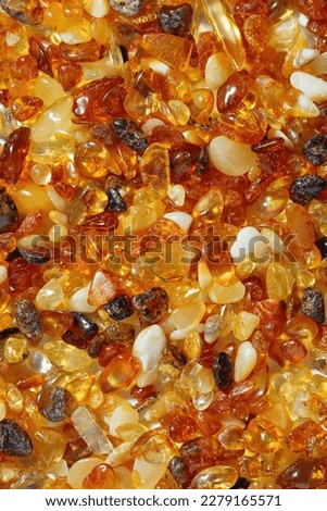 Amber texture background, small stones yellow orange gradient color. Natural gemstone mineral material for jewelry. Top view Amber textured fon. Sunstones pieces ancient resin. Transparent pieces gem.