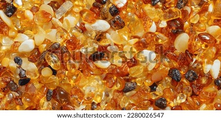 Amber texture banner, small stones yellow orange gradient color. Natural gemstone mineral for jewelry. Top view Amber textured background. Sunstones pieces ancient resin. Transparent pieces gem.