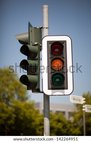 Amber traffic light warning of a progression to a red light bringing trafic to a halt at an intersection