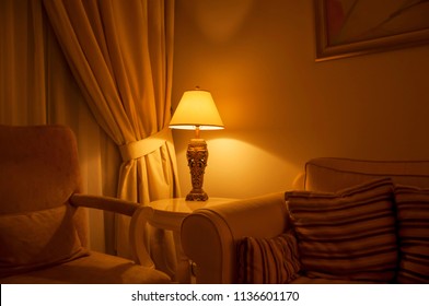 An ambient lighting in the living room. A classic decorative table lamp with shade at the side of the sofa. - Powered by Shutterstock