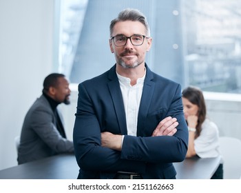 Ambition Gets You Far, I Can Testify To That. Portrait Of A Confident Mature Businessman Standing In An Office With His Colleagues In The Background.