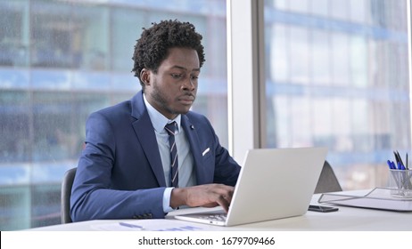 Ambitious African American Businessman using Laptop in Office