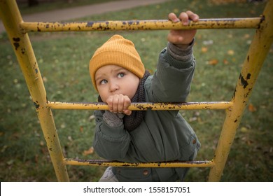 Ambitious, Determined, Motivated Child Boy, Climbing Up Yellow Ladder In Yellow Hat, Looking Up, Striving To Reach The Top, Playing Outdoors In Children Playground