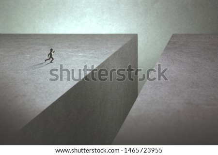 ambitious man taking run up to make a big jump to reach the other side of the precipice