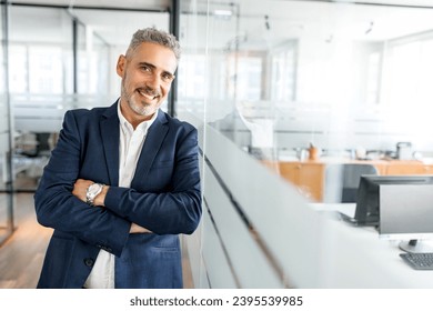 Ambitious mature male entrepreneur ceo manager in formal wear stands in contemporary office space, leaned on glass partition, smiling 50s mature businessman looks at camera - Shutterstock ID 2395539985
