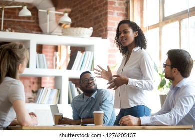 Ambitious smart african black female employee speaking at diverse meeting share creative idea opinion at group briefing while jealous envious skeptical male coworkers looking listening to colleague - Shutterstock ID 1276205137