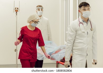 Ambulance Doctors Brought A Patient With A Coronavirus Patient On A Stretcher. Doctors In Protective Suits Take The Patient To The Hospital. Coronavirus Pandemic, Pneumonia