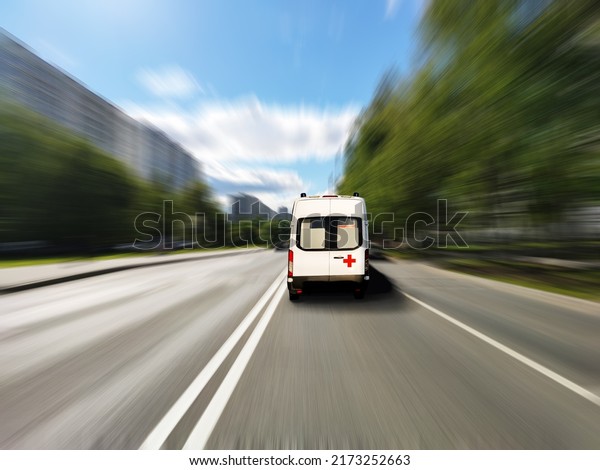 An ambulance, doctors are in a hurry to call, the\
car is in focus, the background is smeared - in motion. Road,\
summer landscape, two lanes, trees, houses, street. Protection of\
human life and health