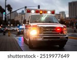 An ambulance with lights activated and a police car behind it  in an urban environment 