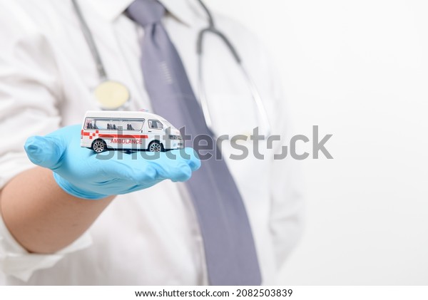 Ambulance model in doctor\
hand isolated on white background, patient transfer service or\
insurance concept