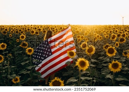 America celebrate 4th of July. Independence Day. Young girl holding bengal fire with American flag at sunset. Patriotic concept