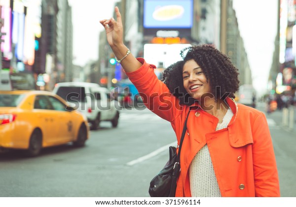 America woman calling a taxi in Manhattan.\
Good mood and hand up to stop the yellow\
cab