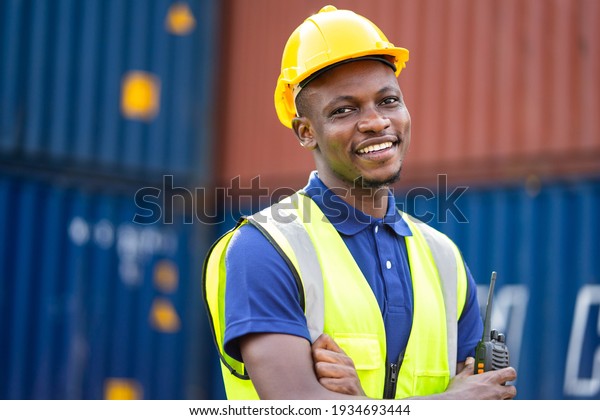 American African engineer or\
factory worker man at Container cargo harbor to loading containers.\
African dock male staff for Logistics import export shipping\
concept.