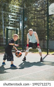 American Basketball Players Athletic Instructor And His Pupil Little Kid Boy In Action In Basketball Court. Dribbling