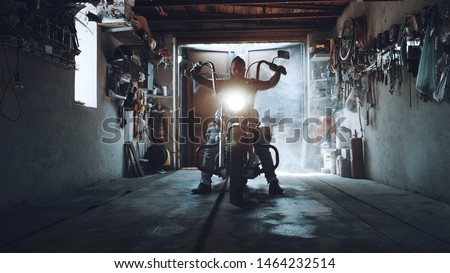 American biker with his motorcycle in the garage. cool and powerful chopper which the biker collected with his own hands