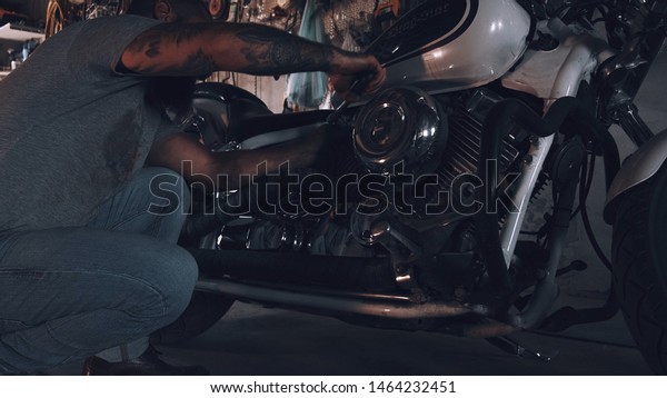 American\
biker with his motorcycle in the garage. cool and powerful chopper\
which the biker collected with his own\
hands
