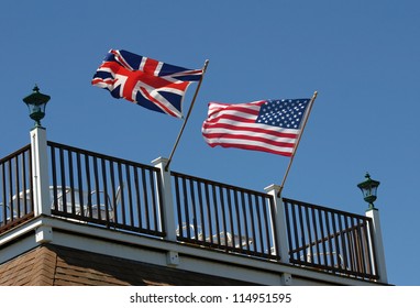 An American and British flag waving in the wind on a rooftop deck