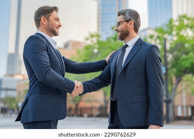 American businessman shaking hands with partner. Two businessmen shaking hands outdoors. Shaking hands. Management strategy. Handshake between two businessmen. Communication of business concept. - Powered by Shutterstock