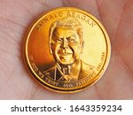 American coin lies on the palm. 1 dollar close up. Obverse coins featuring President Reagan. News about national currency, state budget, Fed, inflation and refinancing rate. Macro