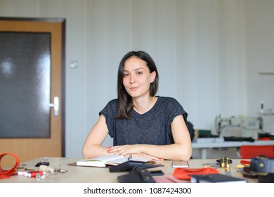 American craftswoman sitting at leather atelier and making handmade notebook, smartphone, tools and materials on table. Concept of home business, handicraft and hobby. - Powered by Shutterstock