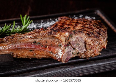 American cuisine. Large juicy grilled steak on a tomahawk bone. Beef steak on a wooden board with rosemary and salt. background image, copy space text - Shutterstock ID 1683573385