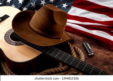 American culture, living on a ranch and country muisc concept theme with a cowboy hat, USA flag, acoustic guitar, harmonica and a rope lasso on a wooden background in a old saloon