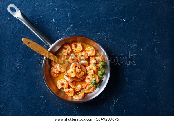 American\
dish for the national shrimp scampi day - cooked with garlic butter\
sauce served with lemon and parsley, on a skillet on concrete\
background, top view, horizontal\
orientation