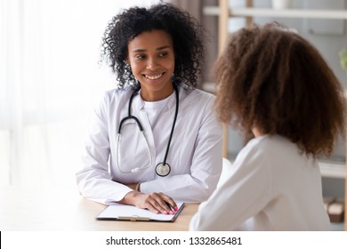 American doctor psychotherapist, therapist counsellor or pediatrist in white coat listens teen girl during reception at clinic. Teen problems, therapy session, adolescent medicine paediatrics concept