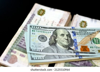 American and Egyptian money banknotes Isolated on a black background, Obverse side of 100 $ One hundred American dollars bill with stack of 200 LE two hundred Egyptian pounds, money exchange rate