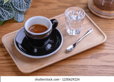 American Espresso Macchiato with Milk and Black Coffee Styled with a Glass of Water, Spoon on a Wooden Serving Tray and Table